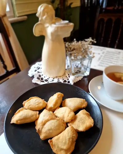 Figurka anioła na stoliku obok talerza pierogów