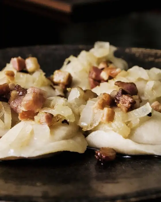 Pierogi gotowane ze skwarkami i cebulką na czarnym talerzu